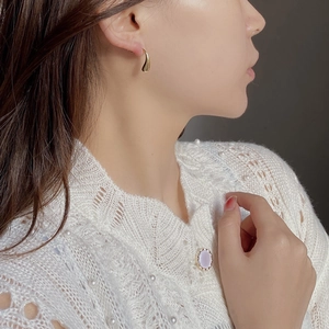 Close-up of a model wearing a polished gold water drop stud earring with a minimalist design