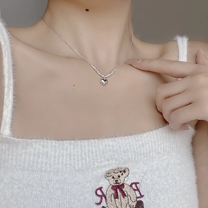 Gros plan d'un collier avec pendentif cœur en argent 925 porté au cou d'une femme
