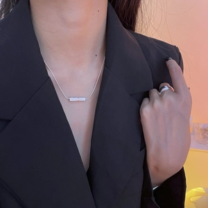 Close-up of minimalist S925 sterling silver pearl necklace and ring on a black blazer