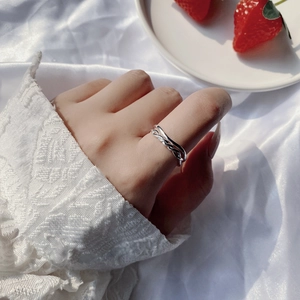 Close-up of minimalist double-layered silver open ring on finger with silk background