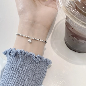 Detailed view of a 925 sterling silver beaded bracelet worn on a wrist with blue knit sleeve
