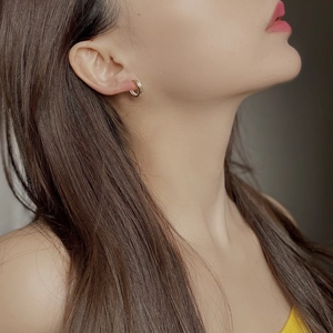 Detail of two-tone layered gold and silver earrings worn on a model ear