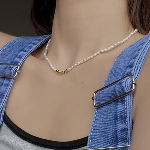Gros plan d'un collier de perles d'eau douce avec perles géométriques dorées