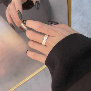 Close-up of S925 sterling silver daisy ring with white enamel petals on a finger