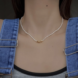 Gros plan d'un collier de perles fines avec trois perles dorées sur un mannequin