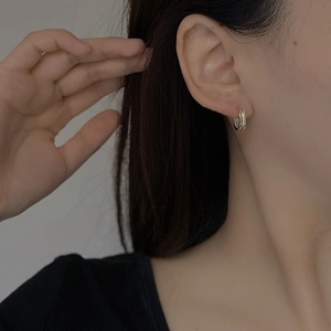 Close-up of minimalist two-tone S925 sterling silver hoop earrings worn by a model