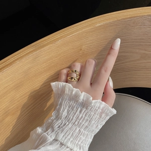 Detailed view of the wavy pleated texture on a vintage gold-plated open adjustable ring
