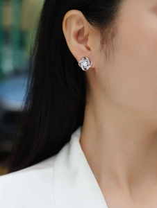 Detailed view of S925 sterling silver twisted floral stud earrings worn on ear model
