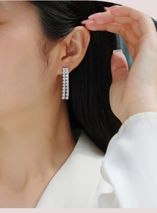 Close-up of elegant double-row moissanite tassel earrings worn on ear by a model