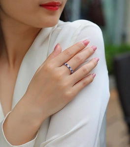 Gros plan d'une bague en argent S925 sertie de saphirs bleus et de gemmes blanches sur un doigt