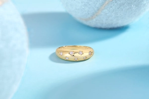 Detail of gold dome ring featuring engraved stars with sparkling zircon stones