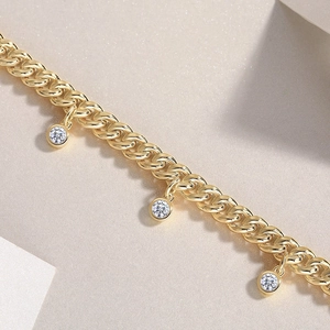 Golden Cuban link bracelet featuring three round bezel-set zircon charms on a textured base