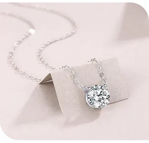 Macro view of round moissanite pendant with four-prong setting on a silver chain