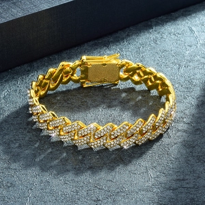 Iced out 14mm Cuban link bracelet with sparkling rhinestones on a textured rock background