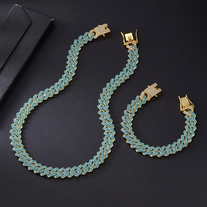 Detail of gold Cuban link chain set with light blue rhinestones on black background