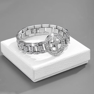 Close-up of iced-out Cuban link bracelet with rhinestone cross emblem on white gift box