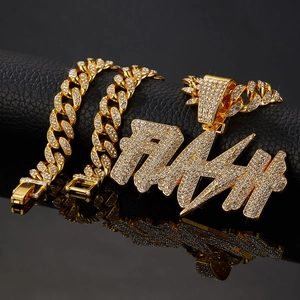 Detailed macro view of iced out golden Cuban chain with RAH crystal letter pendant