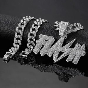 Macro view of silver FLASH letter pendant and Cuban link chain with paved rhinestones