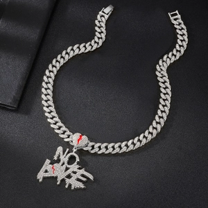 Macro detail of silver iced out NO LOVE letter pendant with red broken heart on Cuban chain