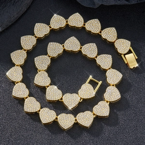 Vue détaillée du collier à maillons cœur 15mm dorés avec strass pavés sur fond noir intense