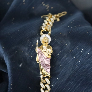 Detailaufnahme des goldenen Panzerarmbands mit glitzernden Strasssteinen und Saint Jude Anhänger