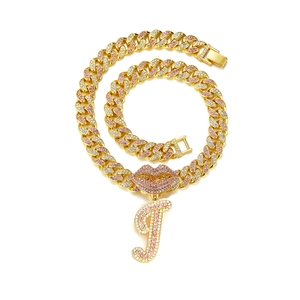 Macro detail of gold Cuban link chain with pink rhinestone lips and letter J pendant