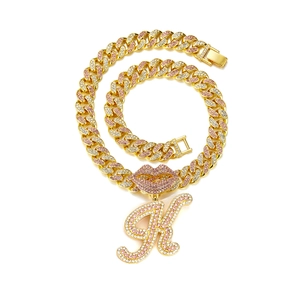 Detailed macro of gold Cuban chain necklace with pink rhinestone lips and letter R pendant
