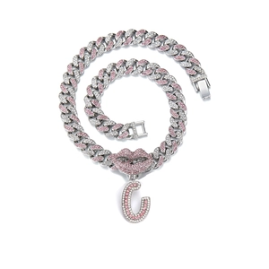 Close-up of pink rhinestone lips and iced-out letter C pendant on a Cuban chain
