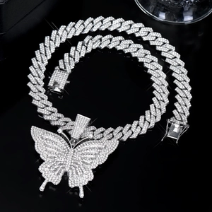 Close-up of iced out cuban link chain and butterfly pendant with sparkling rhinestones