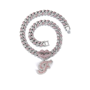 Detail of silver Cuban link necklace featuring pink rhinestone lip and letter F pendant