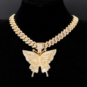 Macro detail of iced-out butterfly pendant and gold plated cuban link chain