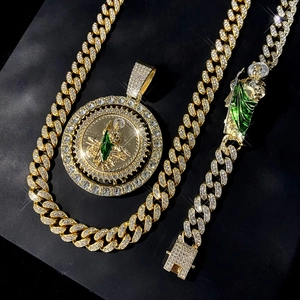 Macro view of iced out St. Jude pendant and Cuban link chain set with green enamel accents
