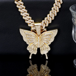 Detailed close-up of golden iced-out butterfly pendant with cuban link chain hip hop style
