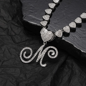 Dettaglio della collana argentata con ciondolo a lettera M con strass e maglie a forma di cuore