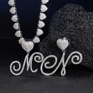 Dettaglio della collana a cuori e orecchini con strass e lettere M e N in argento