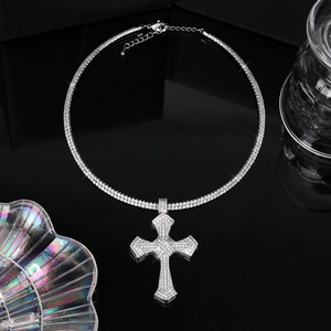 Vue macro d'un pendentif croix hip-hop argenté avec cristaux et chaîne à double rangée