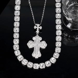 Detail of silver iced-out tennis chain and large rhinestone cross pendant on black surface