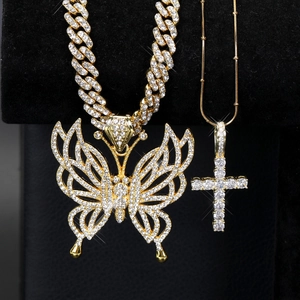 Détail de colliers hip hop dorés avec pendentifs papillon et croix sur support noir