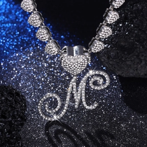 Vista macro del ciondolo lettera M argento con strass e catena a maglie a cuore