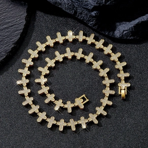 Nahaufnahme der goldenen Hip-Hop-Kreuzkette mit Pavé-Diamanten auf dunklem Felsen