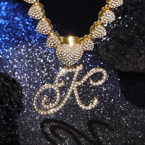 Dettaglio della collana hip-hop con ciondolo lettera K dorata, strass e maglie a forma di cuore