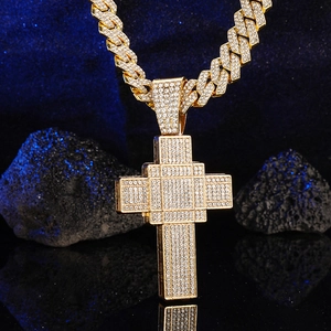Macro detail of iced-out hip hop cross pendant in gold finish with Cuban link chain