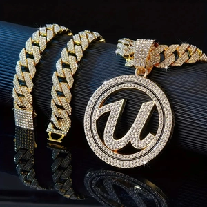 Macro shot of iced out gold plated Cuban chain and sparkling U-letter pendant on black stand