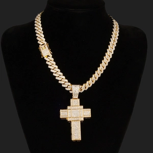 Close-up of hiphop gold Cuban chain with iced-out pixelated cross pendant on black bust