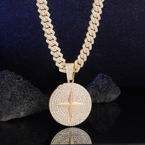 Close-up van gouden Cuban chain met sterhanger op donkere reflecterende vulkanische rots