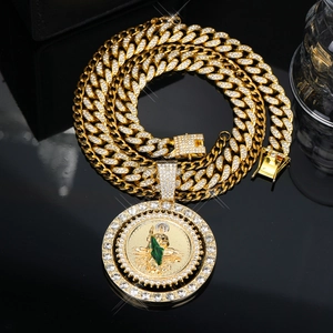 Close-up of gold Cuban link chain with iced-out St. Jude medallion and green enamel