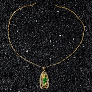 Macro detail of San Judas pendant with green enamel and sparkling rhinestones