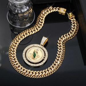 Macro detail of iced-out Saint Jude pendant with green enamel and gold Cuban link chain