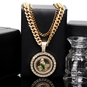 Close-up of gold Cuban chain with iced-out St. Jude pendant and green enamel details