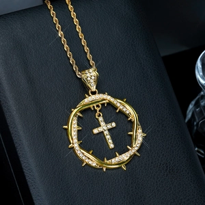 Golden thorn crown cross pendant necklace with sparkling diamonds on a black jewelry box